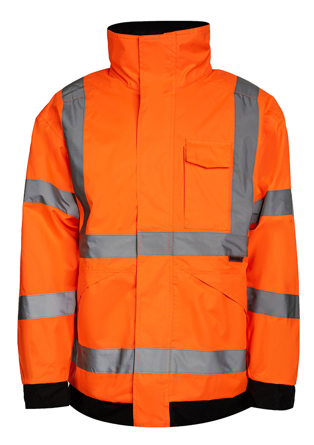 Erwachsener Bauarbeiter in gelber Korntex Hochsichtbarkeits-Regenjacke und gelbem Schutzhelm trägt eine Schaufel auf einer Baustelle.