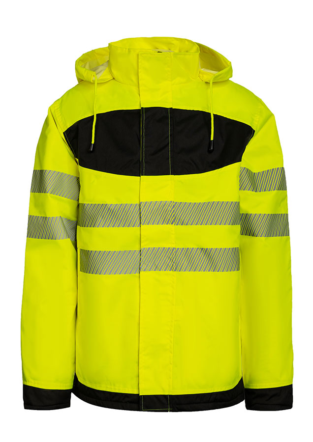 Erwachsener in signalgelbem Korntex-Parka mit schwarzer Brustpartie und Reflexstreifen in einem industriellen Umfeld