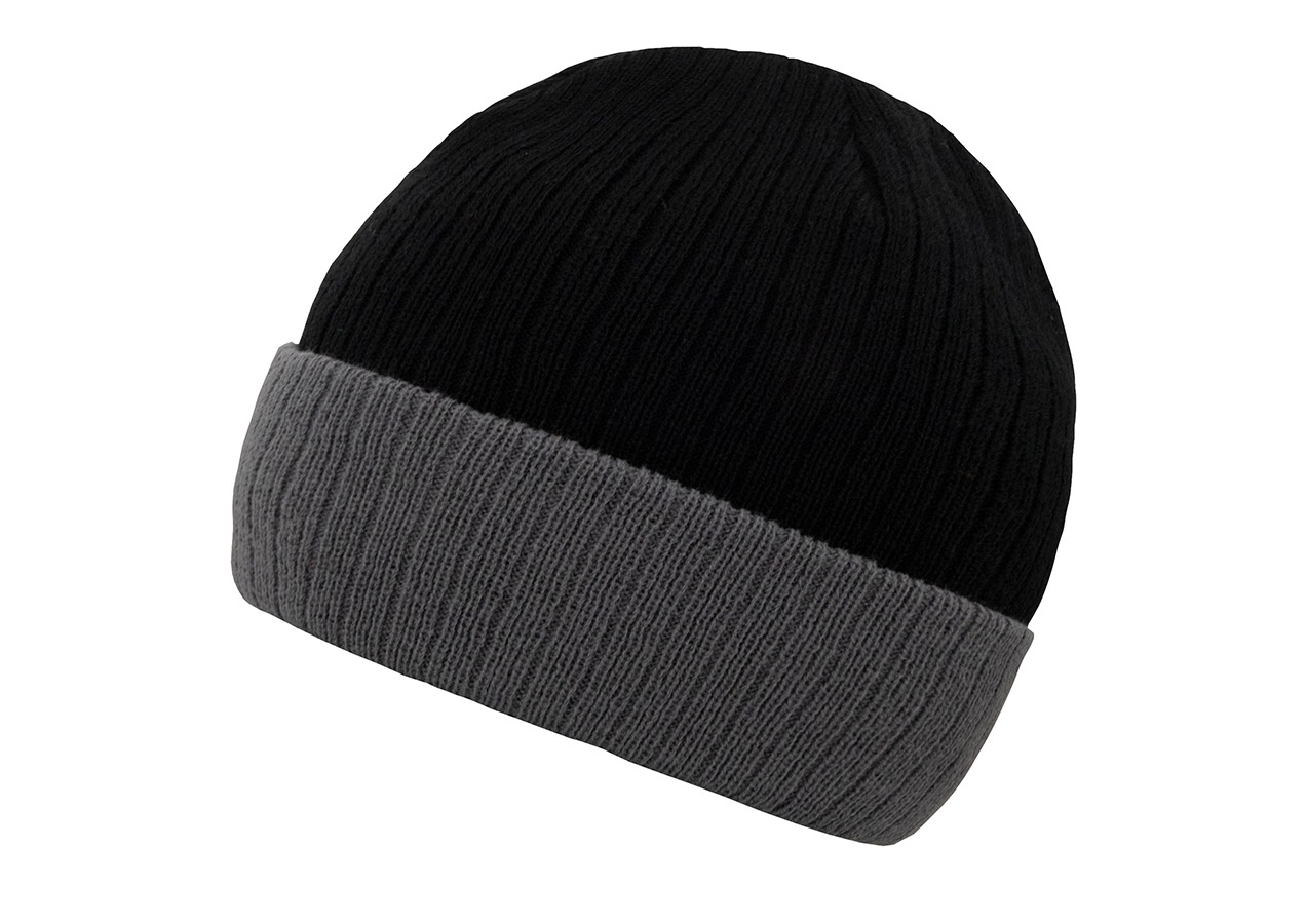 Ein Erwachsener trägt eine bestickbare, schwarz-graue Korntex-Strickmütze vor einer grauen Wand