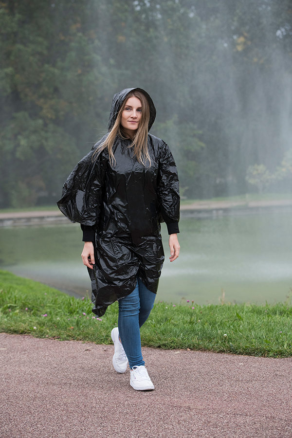 Erwachsene Frau trägt einem schwarzen Korntex Poncho in einem Park