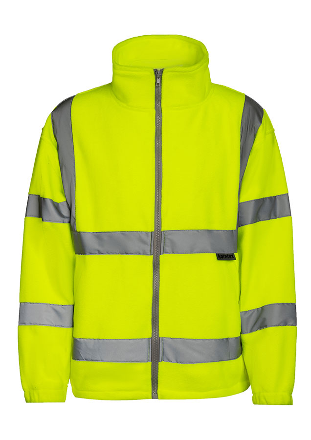 Erwachsener Mann läuft in signal-oranger Korntex Warnschutz-Fleecejacke mit Reflexstreifen vor einem Industriegebäude entlang.