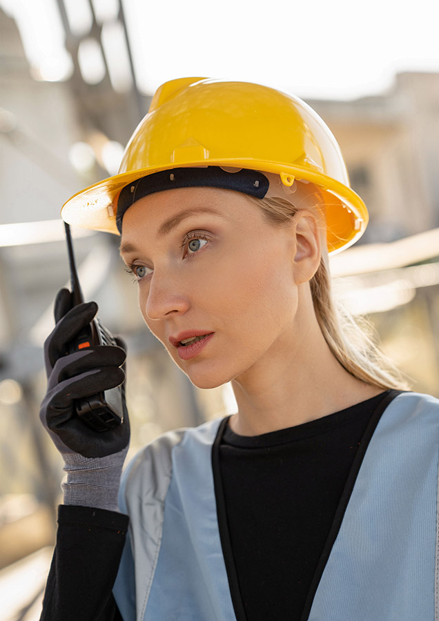 Eine Frau trägt einen Korntex-Schutzhelm, während sie in ein Walkie-Talkie spricht