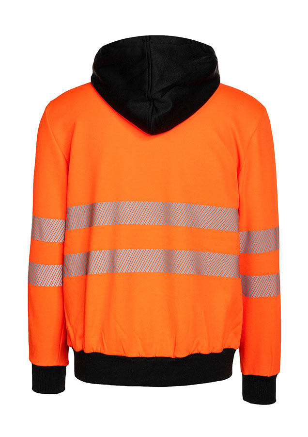 Erwachsener trägt einen orangefarbenen Korntex-Hoodie mit schwarzer Brustpartie in einem industriellen Umfeld