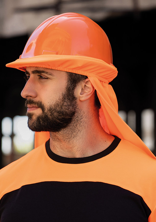 Ein Mann trägt einen orangefarbenen Korntex-Helm mit UV-Schutz, während er in einer Baustellenumgebung steht