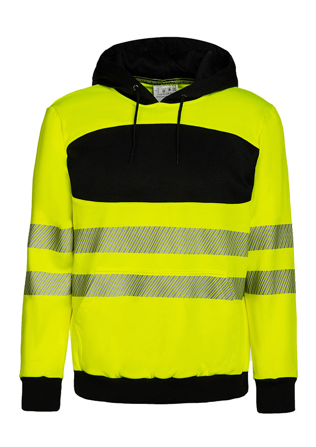 Erwachsener trägt einen orangefarbenen Korntex-Hoodie mit schwarzer Brustpartie in einem industriellen Umfeld
