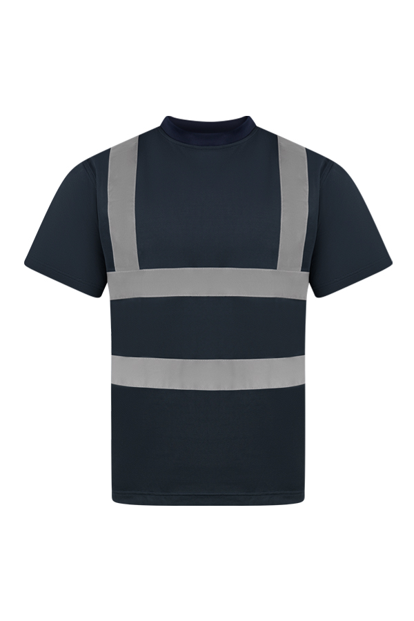 Erwachsene Frau steht in signal-orangenem Korntex Warnschutz-T-Shirt und weißem Schutzhelm vor einem Gerüst auf einer Industriebaustelle
