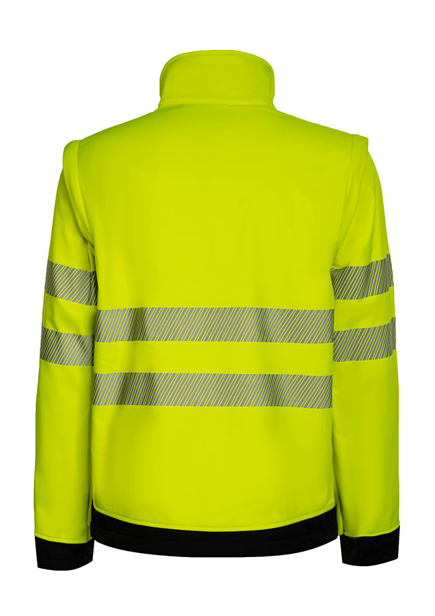 Erwachsener in signalgelber Korntex-Softshell Jacke mit schwarzer Brustpartie und Reflexstreifen in einem industriellen Umfeld