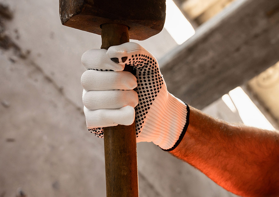 Männliche Hand die einen Arbeitshandschuh Konya trägt mit einem Hammer in der Hand