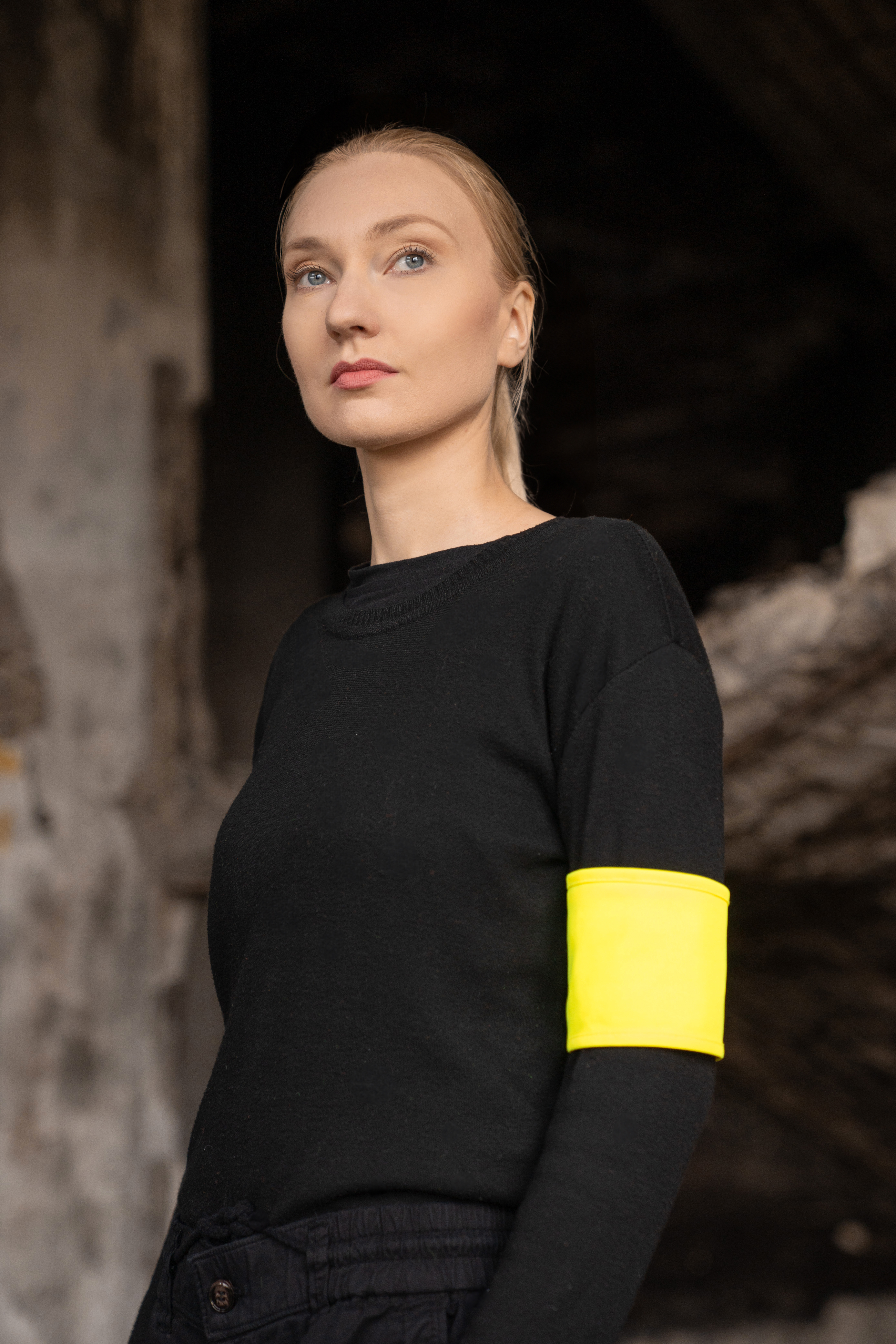 Porträt einer jungen Frau mit reflektierender gelber Korntex Armbinde in einer Industrieruine