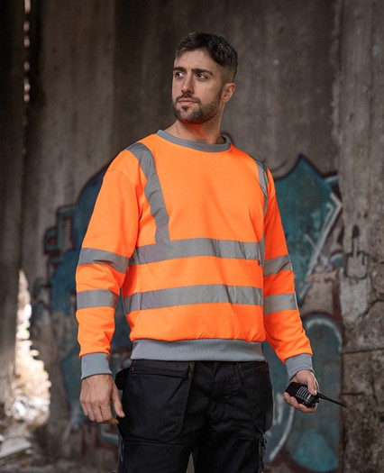 Mann mit orangenem Sweatshirt unter einer Brücke.