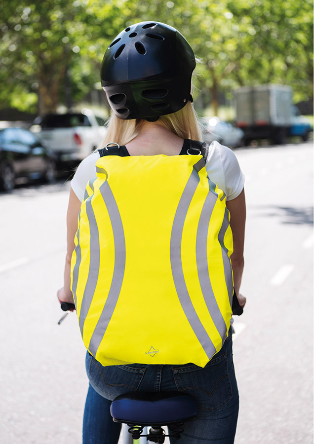 Eine Frau mit gelbem Korntex-Rucksacküberzug mit Reflexstreifen fährt Fahrrad