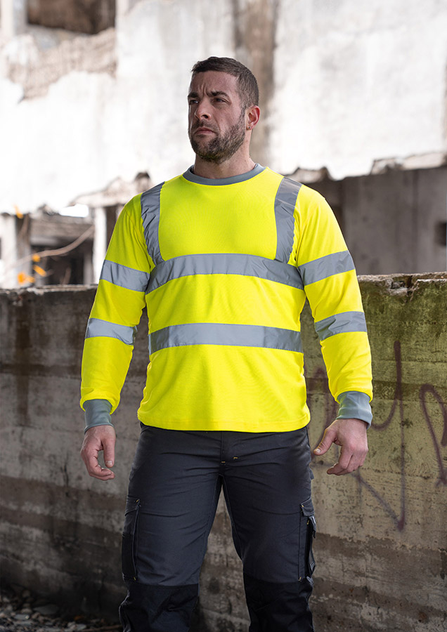 Erwachsener in signalgelbem Korntex-Long-Sleeve mit Reflexstreifen auf einer Baustelle