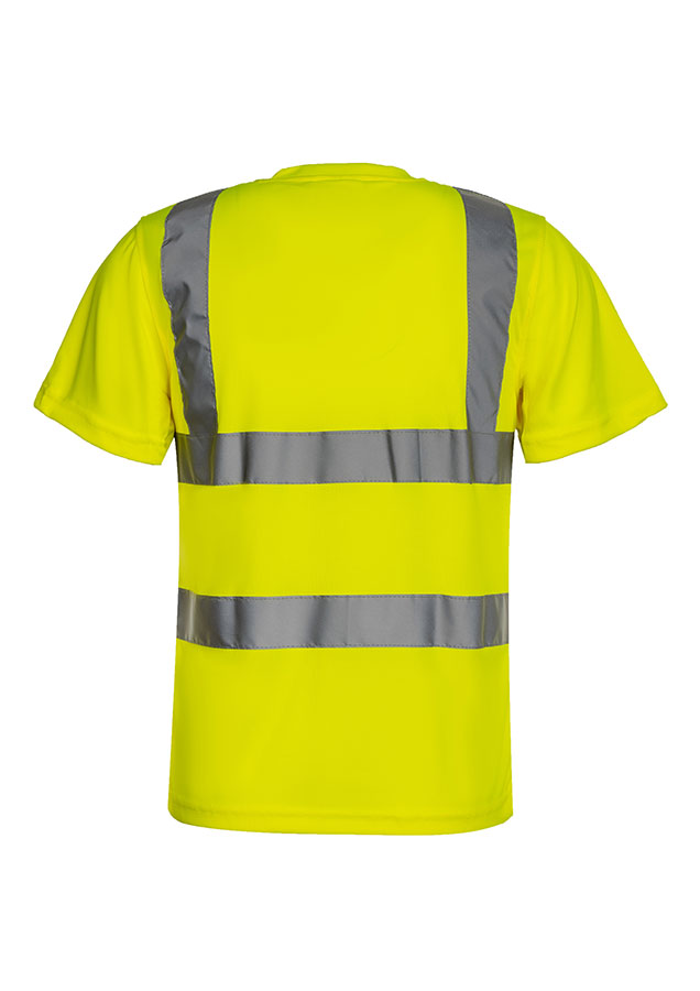 Erwachsene Frau steht in signal-orangenem Korntex Warnschutz-T-Shirt und weißem Schutzhelm vor einem Gerüst auf einer Industriebaustelle